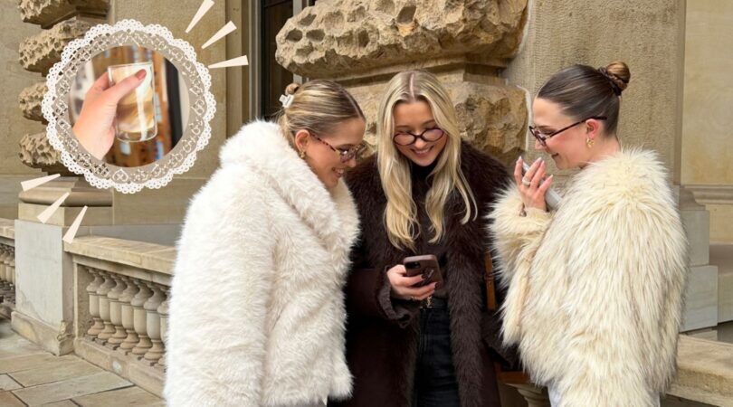 Foto van drie meiden die nieuwsgierig en giechelend naar hun telefoon kijken.