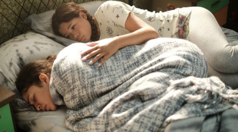 Sc&egrave;ne uit Euphoria. Twee meiden liggen op bed. De een heeft buikpijn, de ander troost haar.