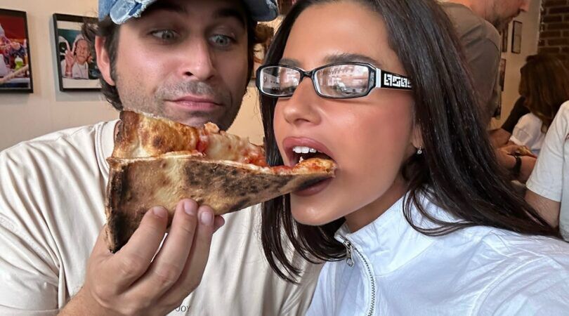 Man voert een stuk pizza een vrouw.