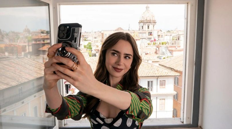 Lily Collins in de serie Emily in Paris. Ze neemt een selfie.