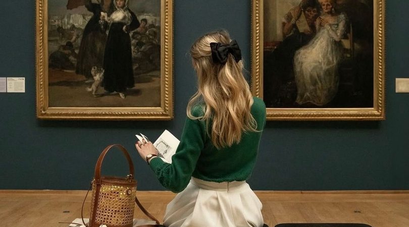 Meisje zit in een museum, ze leest een boek.