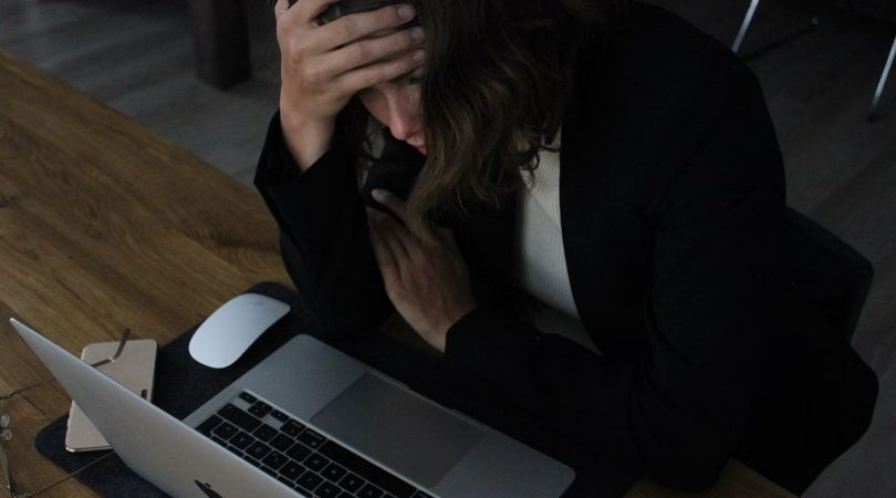 Vrouw die gestresst achter haar laptop zit.