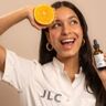 Jonge vrouw met een sinaasappel en een Vitamine C serum in haar handen.