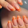 Twee handen met oranje nailart op de nagels.