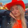 Meisje met een oranje shirt, een oranje cowboyhoed en een leren jasje.