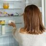Vrouw haalt kliekjes uit de koelkast.