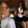 Twee vrouwen die lachen en koffiedrinken.