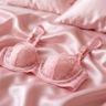 Roze bh op satijnen dekbed.