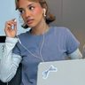 Influencer Kika Lateef zit achter laptop, ze doet haar oortje uit.