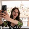 Lily Collins in de serie Emily in Paris. Ze neemt een selfie.