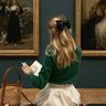 Meisje zit in een museum, ze leest een boek.