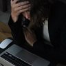Vrouw die gestresst achter haar laptop zit.
